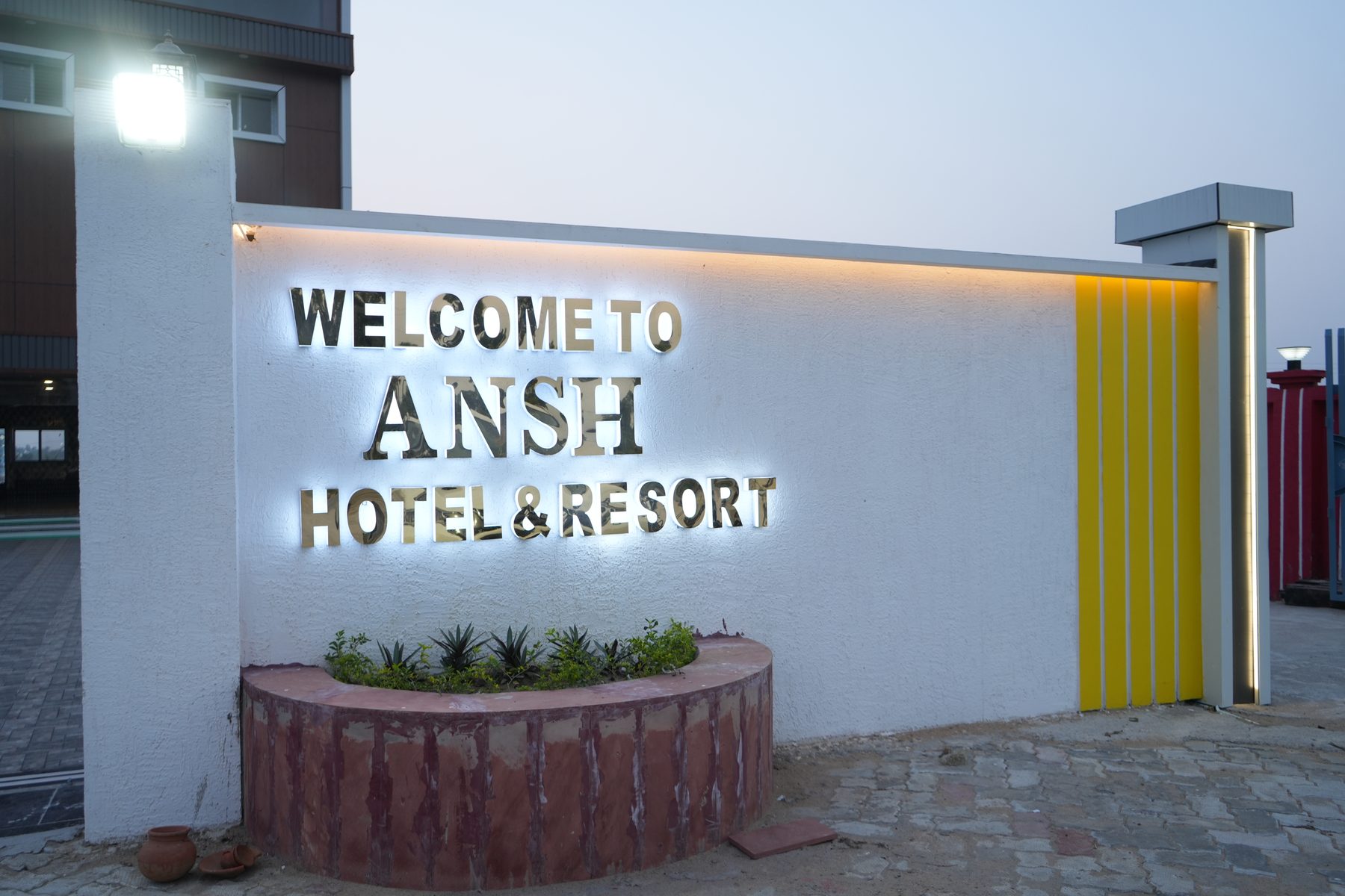 Illuminated welcome sign at the entrance of Ansh Hotel & Resort